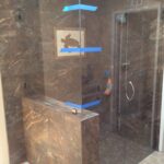 glass shower door installation with beautiful tile and turtle